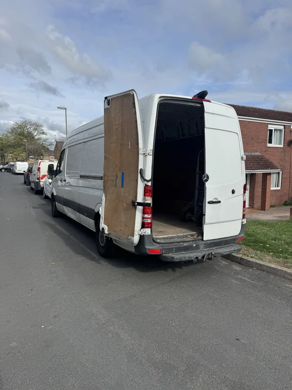 White removal van parked on a residential street with its rear doors open