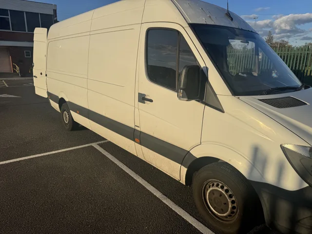 White long-wheelbase removal van parked outside a building